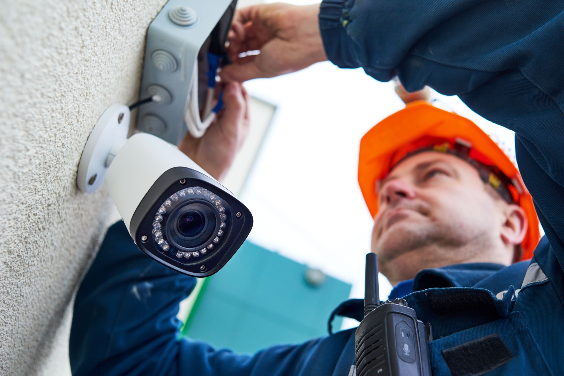 Technician worker installing video surveillance camera on wall Technician worker installing video surveillance camera on wall